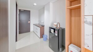 A modern kitchen with a refrigerator, sink, and wooden shelving unit. - Relaxing And Cozy Studio Patraland Amarta Apartment (Ngaglik)