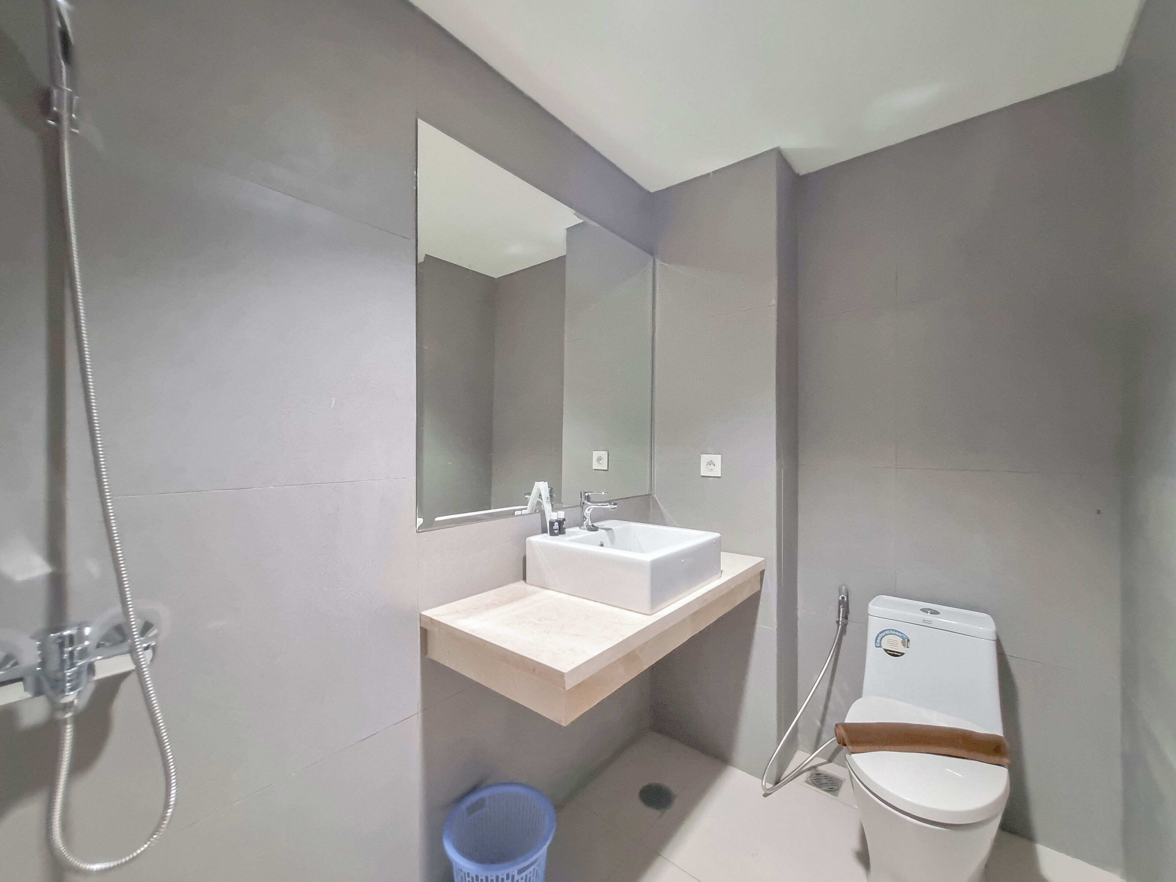 Un baño moderno con lavamanos, espejo, inodoro y ducha.