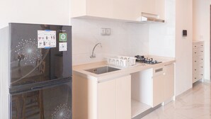 A modern kitchen with a black refrigerator, white cabinets, a sink, and a stove. - Best Place And Homey 2Br Sky House Bsd Apartment Near Aeon (Pagedangan)