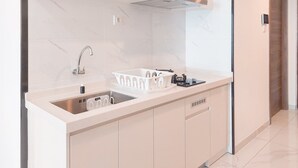 A modern kitchen with a built-in sink, stainless steel faucet, and a dish drying rack. - Best Spacious And Homey 3Br Sky House Bsd Apartment (Pagedangan)