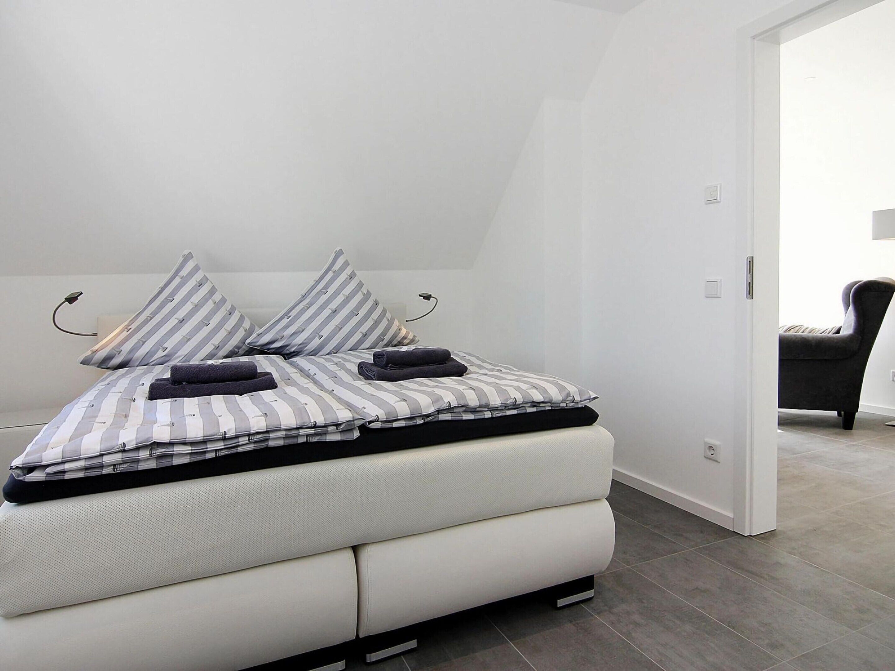 A modern bedroom with a bed, pillows, and a chair.