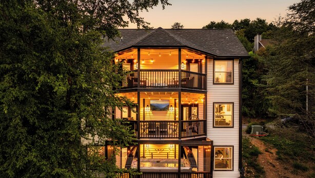 A multi-level house with a balcony, outdoor seating, and a hot tub.