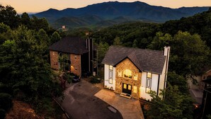 A two-story stone house with a stone chimney, a garage, and a driveway.