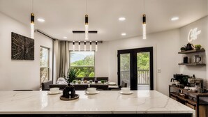 A modern kitchen with a marble countertop, pendant lights, and a coffee sign.