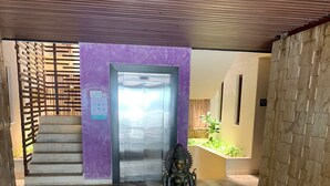 A statue in a courtyard with a tiled floor and a purple wall in the background.