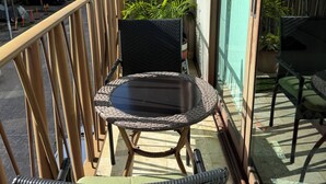 A balcony with a wicker chair, a small table, and potted plants.