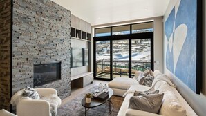 Una sala de estar moderna con una pared de piedra, un ventanal con vistas, un sofá y una mesa de centro.