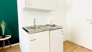 Une cuisine de taille réduite, équipée d’un évier à deux bacs, d’une cuisinière et d’un petit réfrigérateur.