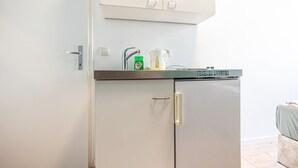 Een kleine keuken met een koelkast, een koffiezetapparaat en een kastje boven het aanrecht.