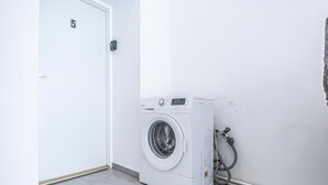 Een wasserette met een wasmachine, een deur met het nummer 5 en een slang.