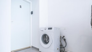 Une buanderie équipée d’un lave-linge, d’une porte portant l’inscription « 5 » et d’un tuyau.