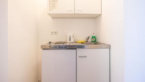 Une petite cuisine équipée d’un réfrigérateur, d’un four à micro-ondes, d’une machine à café et d’un flacon de liquide vaisselle.