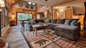 Un intérieur de chalet chaleureux avec un grand canapé, une table à manger et un coin cuisine.