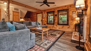 L’intérieur d’un chalet confortable, avec un canapé, une table basse et un plancher en bois.