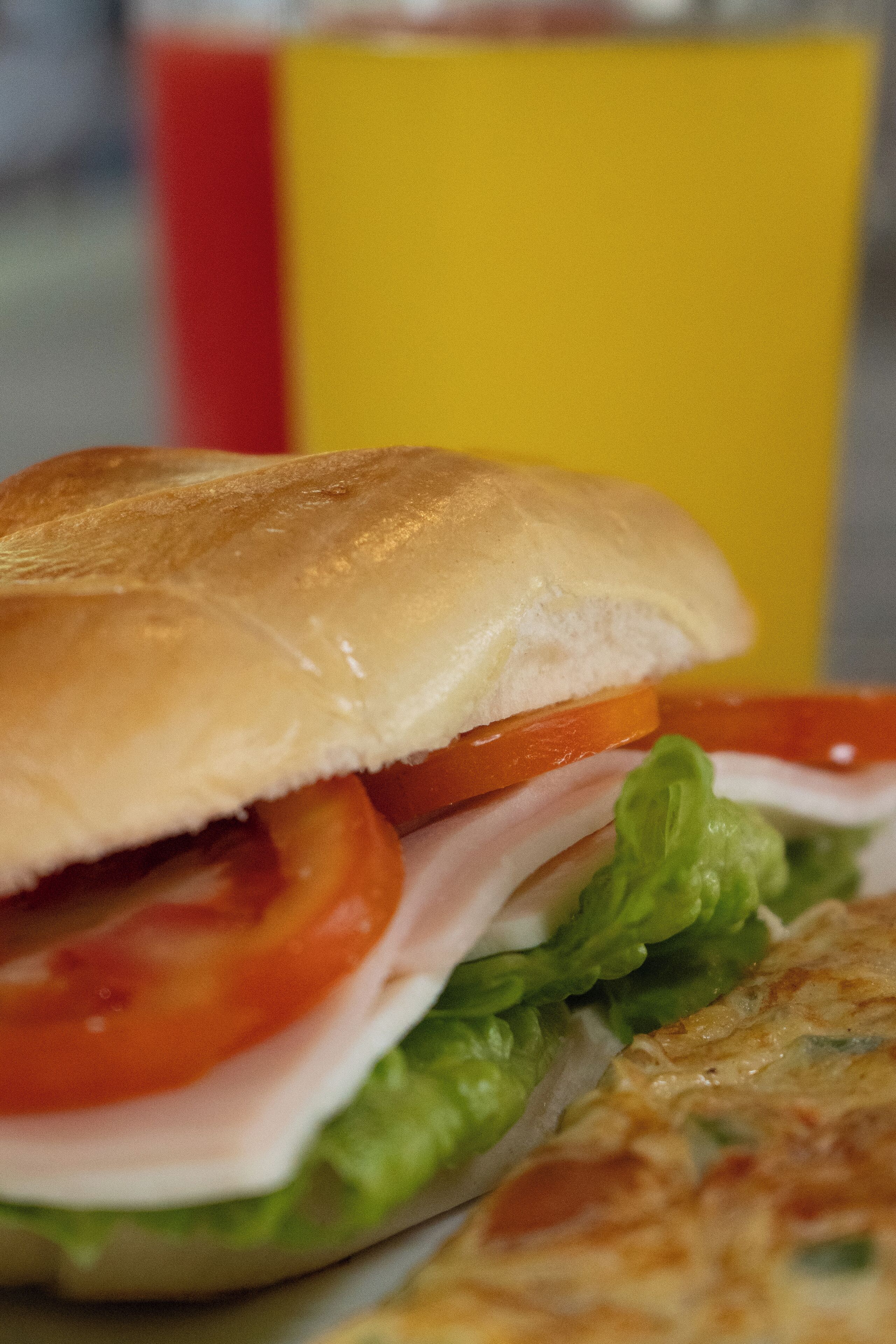 Een sandwich met sla, tomaat en vlees, met erbij een gebakken gerecht.