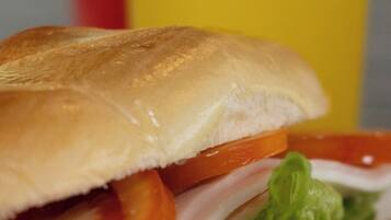 Een sandwich met sla, tomaat en vlees, met erbij een gebakken gerecht.