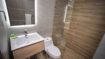 Un baño moderno con un tocador de madera, un lavamanos blanco y un inodoro.