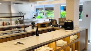 Una cocina moderna con encimera de mármol, estanterías de madera y una cafetera.