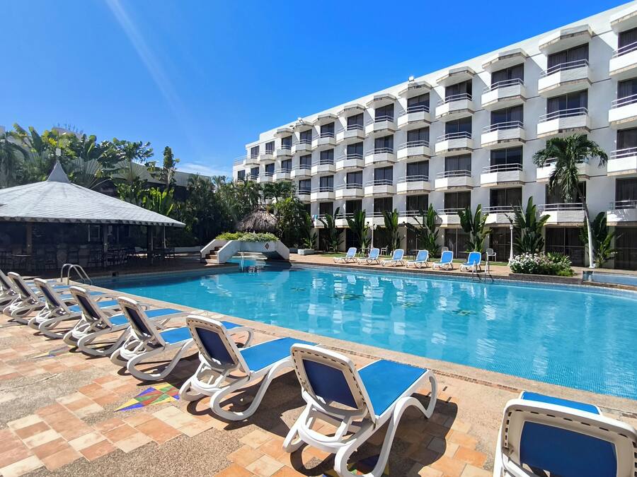 A hotel pool area with lounge chairs and a building in the background.