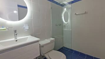 A modern bathroom with a white sink, toilet, and glass-enclosed shower.