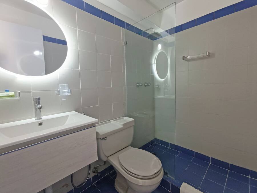 A modern bathroom with a white sink, toilet, and glass-enclosed shower.