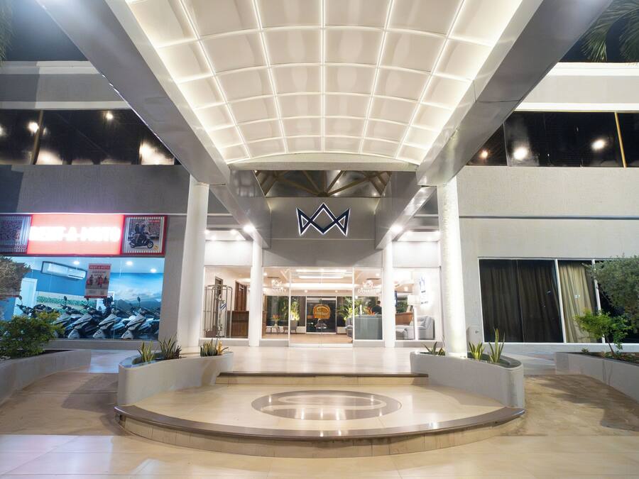 Una entrada de edificio moderna con un atrio central, amplias ventanas y un logotipo destacado sobre la entrada.