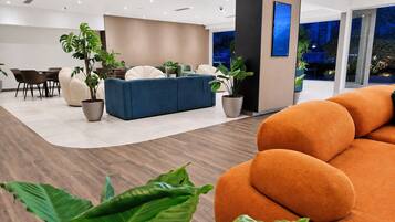 A modern interior with a sofa, dining table, chairs, and potted plants.