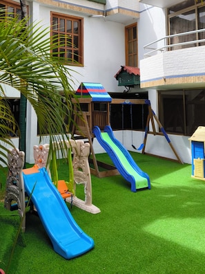 Zona de juegos infantiles con toboganes y columpios.