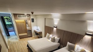 Habitación de hotel con dos camas, un escritorio y una kitchenette pequeña.