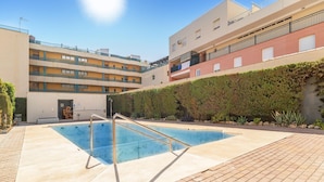 A swimming pool with a metal ladder, surrounded by a paved area with a brick border.