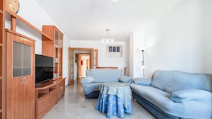 A living room with a sofa, a TV, wooden cabinets, and a round table.
