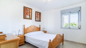 A bedroom with a wooden bed, a wooden dresser, a nightstand, and two framed paintings on the wall.