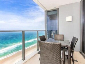 Un balcone con vista sull'oceano, una porta vetrata e un tavolo con sedie.