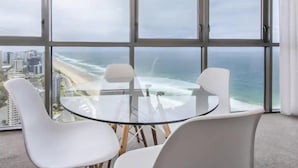 Une chambre moderne dotée d’une grande baie vitrée offrant une vue panoramique sur la plage et le paysage urbain.