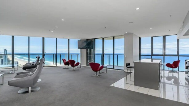 A spacious lounge with a view of the ocean, modern seating, and a flat-screen TV. - Oceanfront at Rhapsody by Coastal Letting Co (Surfers Paradise)