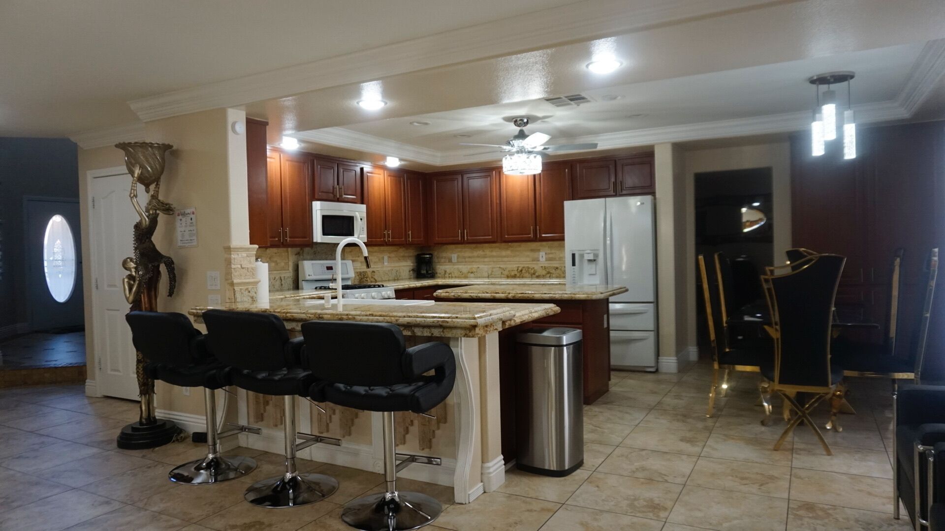 Una cocina amplia con una isla central, taburetes de bar y un refrigerador.