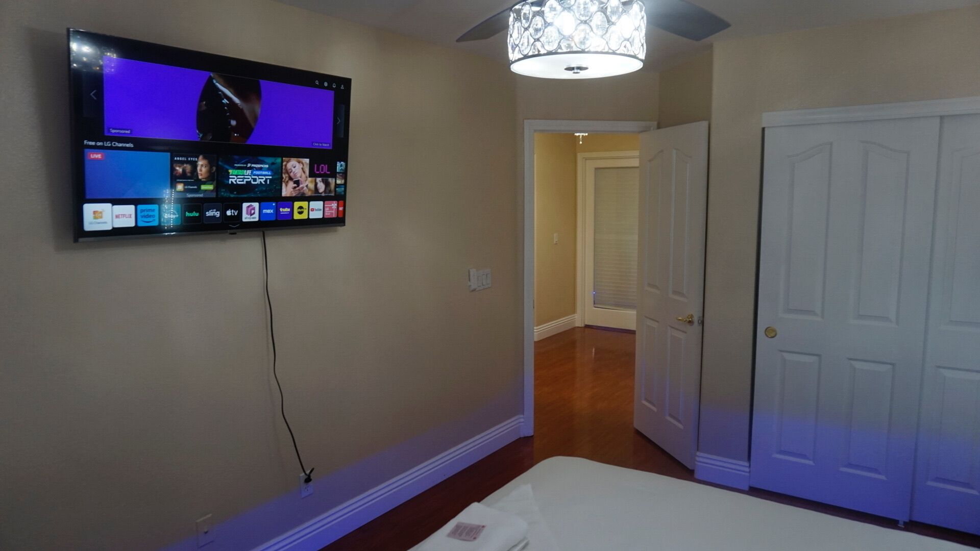 A hotel room with a flat-screen TV mounted on the wall displaying various channels and a selection of movies.