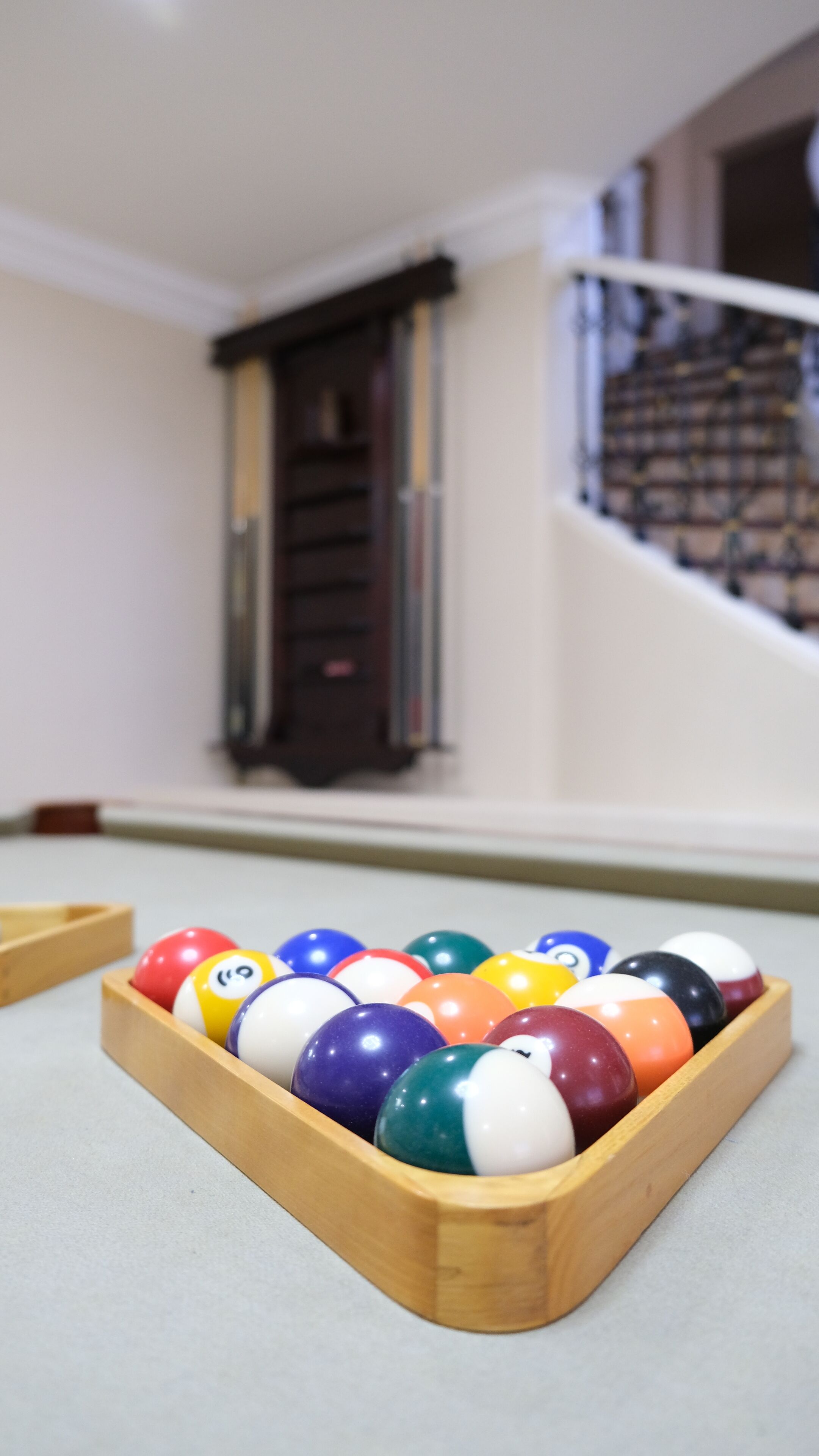 A pool table with a wooden rack filled with colorful billiard balls.