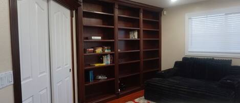 A living room with a dark-colored sofa, a wooden bookshelf, and a white door.