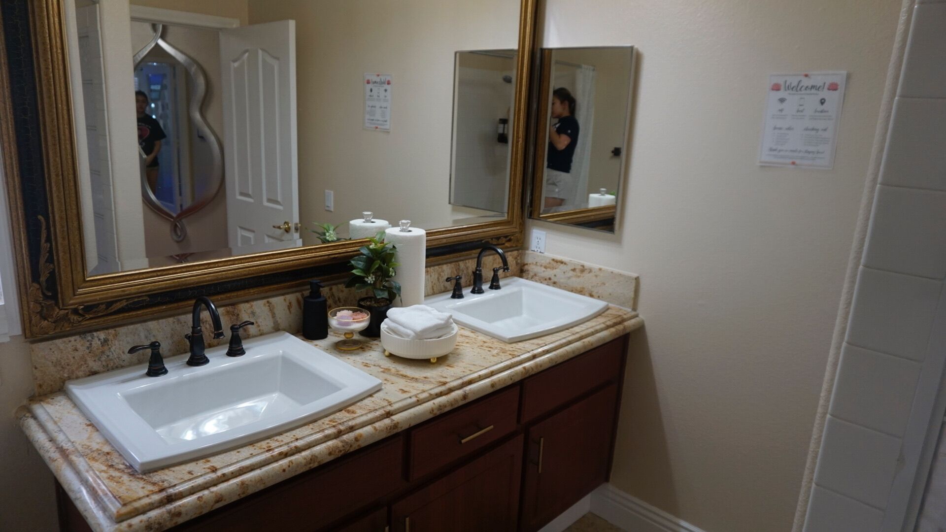 Une salle de bain avec deux lavabos, un grand miroir et une porte.