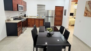 A modern kitchen with a dining area, featuring a central island, built-in appliances, and a contemporary pendant light. - “Your Perfect Getaway: Brand-New Condo in Cabo San Lucas” (Cabo San Lucas)