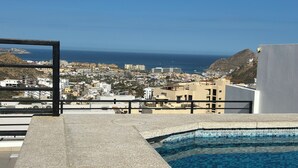 A swimming pool with a view of a coastal town and the sea. - “Your Perfect Getaway: Brand-New Condo in Cabo San Lucas” (Cabo San Lucas)