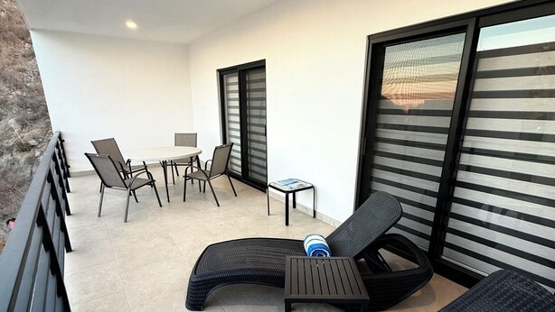 A balcony with two lounge chairs, a small table, and a chair. - “Your Perfect Getaway: Brand-New Condo in Cabo San Lucas” (Cabo San Lucas)
