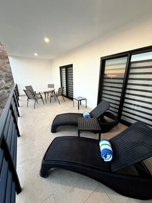 A balcony with two lounge chairs, a small table, and a chair. - Cozy 2BDR- Rooftop pool & jacuzzi- Ocean View (Cabo San Lucas)