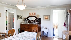 A room with a dining table, chairs, a wooden dresser, a mirror, and a chandelier.