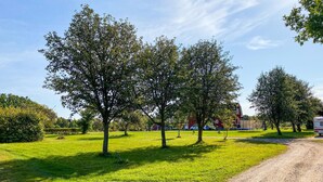 A rural landscape with a dirt path, green grass, and trees.