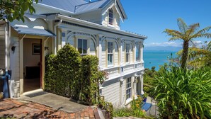 A Victorian-style house with a balcony overlooking a scenic view.