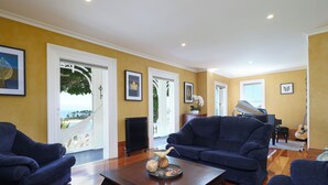 A living room with two blue sofas, a coffee table with decorative items, and a piano in the background.