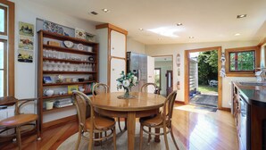 A dining area with a wooden table, chairs, and a bookshelf filled with various items.