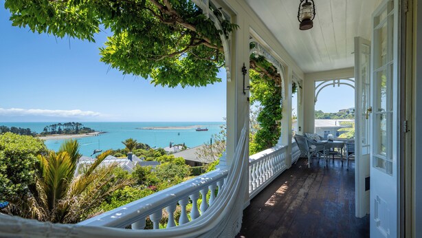 A covered porch with a view of the ocean and a distant island.